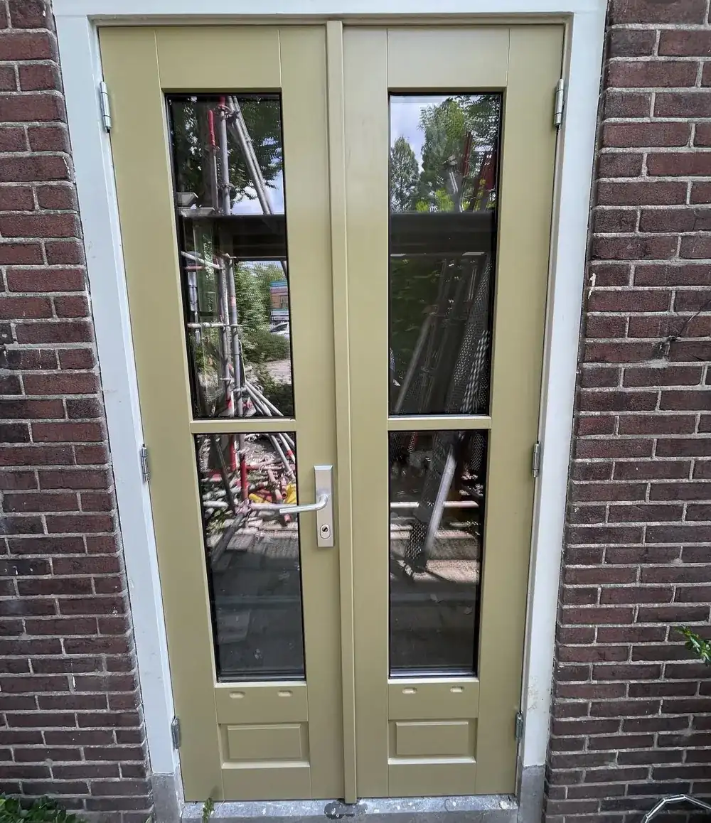 Houten openslaande tuindeuren met glas in een gemetselde gevel